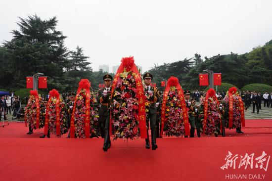 （14名礼兵抬起花篮，将花篮敬放在烈士纪念塔前。）