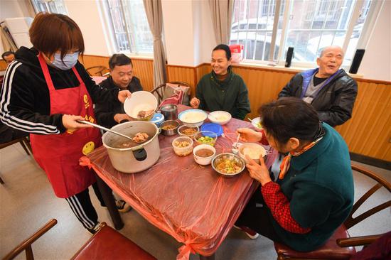 10月21日，在长沙市天心区赤岭路社区文化活动中心，工作人员（左一）为老人盛汤。新华社记者 陈泽国 摄 