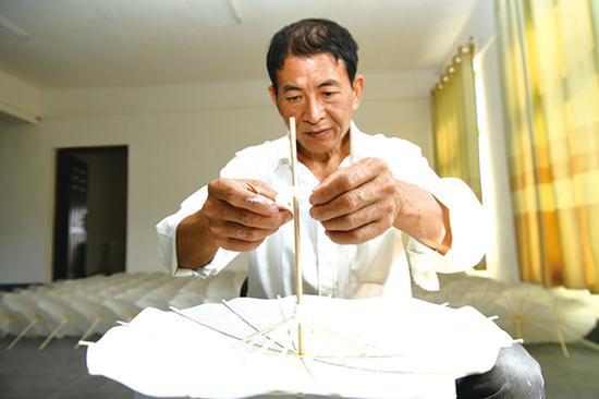 李忠国在生产车间里制作油纸伞。浏阳日报记者 彭红霞 摄