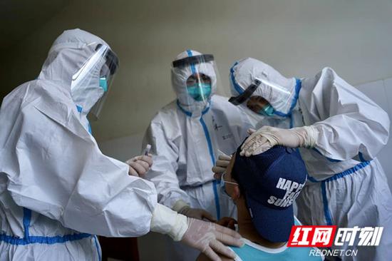 援非医疗队员们正在给赴华人员做咽拭子取样。