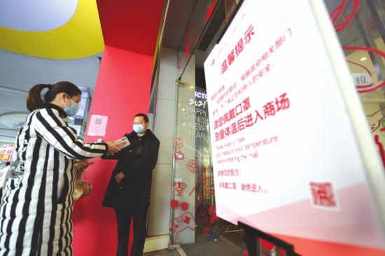 1月19日，长沙悦方IDmall，准备进入商场的顾客不仅戴着口罩，还给安保人员出示健康码，并让其量体温。图/记者吴琳红