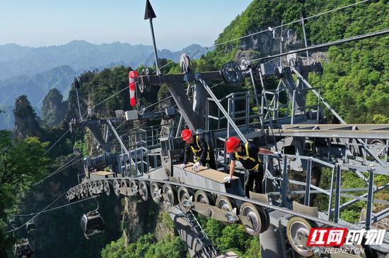 武陵源景区天子山索道检修工人在高空支架上检查索道机件设备。