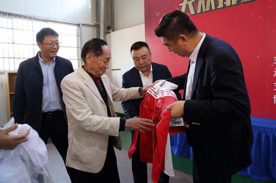 2018年，国家排球运动管理中心主任李全强（右一）向袁老赠送中国女排的队服。王德璠/摄