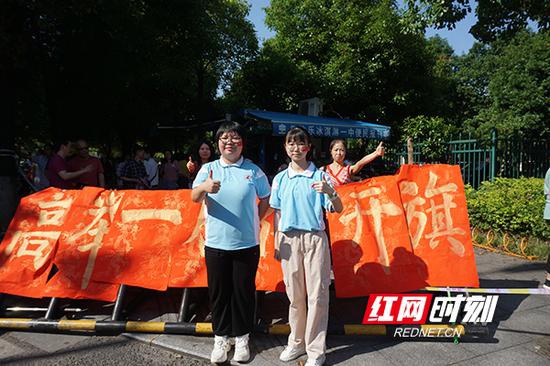 衡阳市一中高一学子封语怡手写祝福语，与同学李昕蓉一起为学长学姐加油。