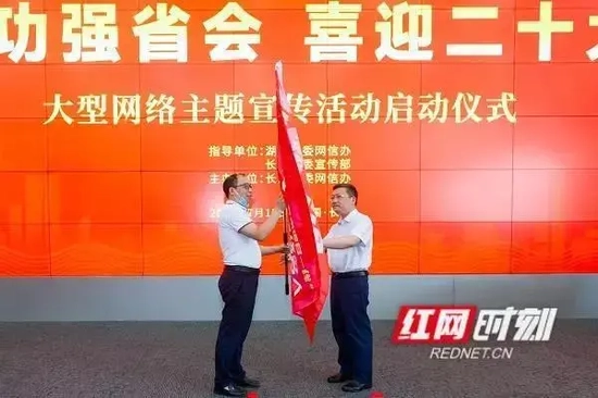 市委常委、市委宣传部长陈澎（右）向出席活动代表红网长沙站站长谭忠欣授旗。
