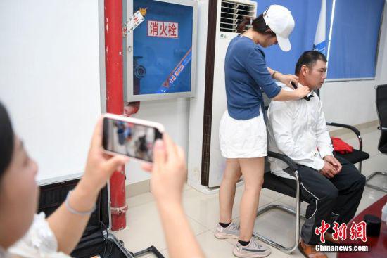 刘萍拍摄丈夫唐金龙化妆，唐金龙是一位塔吊指挥员。 杨华峰 摄