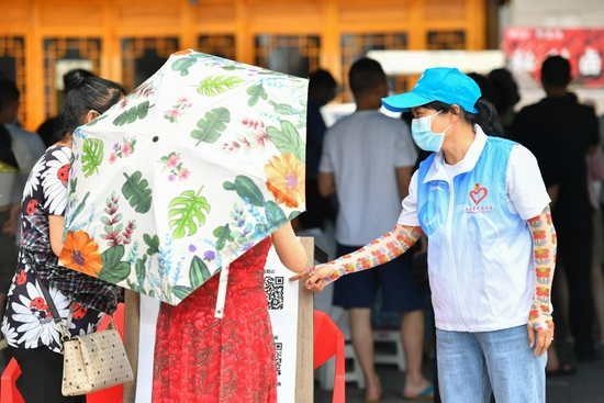 7月31日，在长沙市天心区赤岭路街道白沙花园社区核酸检测点，志愿者引导居民在核酸检测取样前扫码登记身份信息。新华社记者 陈泽国 摄