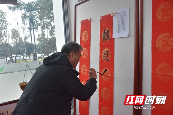 书画名家在壁上书写春联，饱含深情地写下新年寄语。