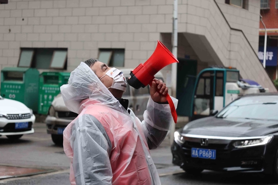 志愿者列提普·图热手持小喇叭通知居民前往社区进行核酸采样。李丹摄