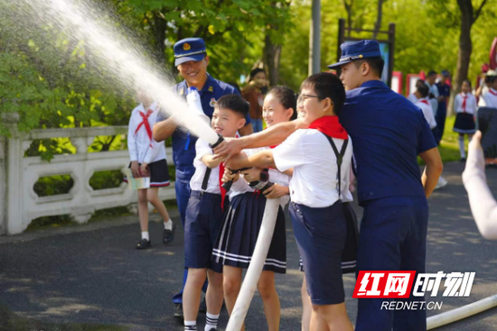 学生们在消防员叔叔指导下使用消防水枪。(图片来源:红网时刻)