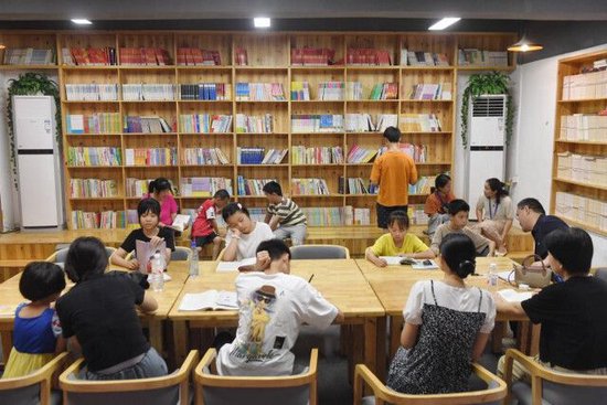 (7月8日,华容县实验小学安置点,青少年在家长陪伴下来到校园书屋阅读和自习。 湖南日报全媒体记者 徐行 摄)