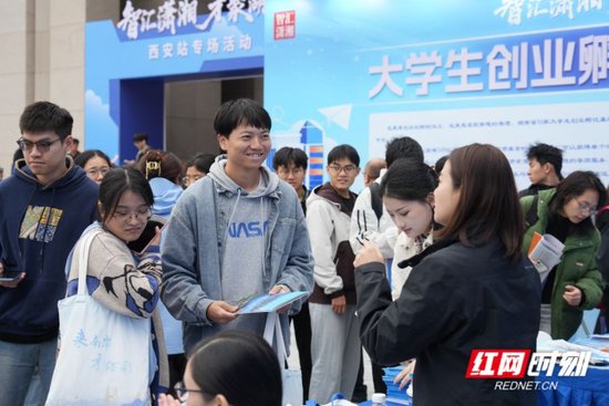 招聘现场，学生向工作人员咨询就业事项。