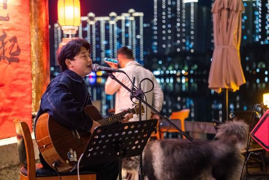 3月10日，歌手在穿紫河畔的常德河街弹唱。 新华社记者 陈思汗 摄