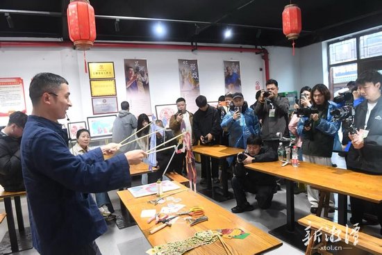 采风团在窑湾历史文化街区观看湘潭纸影戏。（全媒体记者 陈旭东 摄）