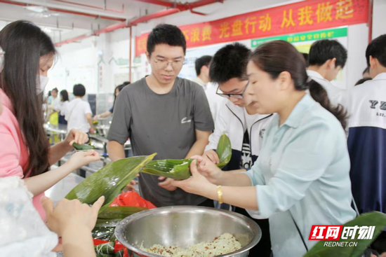 家长与学生一起包粽子。