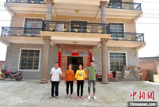 涟源市桥头河镇石狗村的贫困户颜四林一家在自家新房前合影。 刘新山 摄