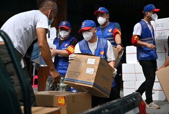 （8月9日，浙江温州的游客陈义（中）在三亚市一间医疗物资仓库搬运医疗物资。新华社记者 郭程 摄）