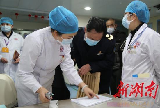 1月23日,省卫生计生综合监督局局长、党委书记张辉(左一)在湖南省脑科医院门诊大厅查看发热患者预检分诊登记表。黄栋 摄
