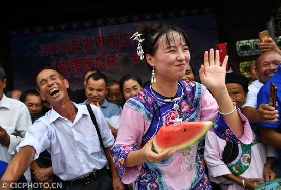 ↑在湖南省湘西土家族苗族自治州花垣县双龙镇岩锣村西瓜节活动现场，人们在进行“吃瓜”比赛。CICPHOTO/龙恩泽 摄