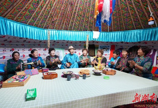 7月18日,新疆维吾尔自治区和布克赛尔蒙古自治县江格尔广场,人们在蒙古包里听江格尔齐(左四)演唱《江格尔》史诗。