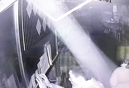 　12月3日凌晨1点半，长沙岳麓区滨江农贸综合直销市场，犯罪嫌疑人正在贴用来覆盖的支付宝二维码。 视频截图