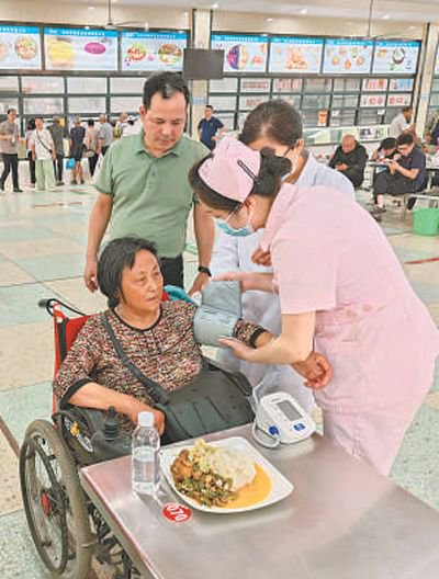 7月6日，在湖南省岳阳市华容县职业中专安置点，医护人员为转移群众测量血压。 　　喻熙荣摄（人民视觉）