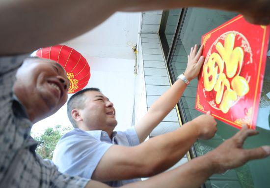 2020年7月23日,衡阳县渣江镇黄冈村贫困群众迁新居,村、镇工作人员在帮助住户贴窗花。衡阳县宣传部供图