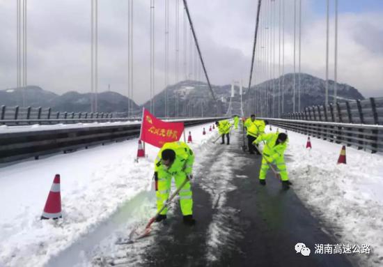 △近日,湘西吉首矮寨大桥,工作人员正在桥面上铲除积雪。