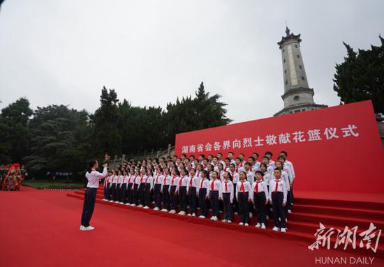 （少先队员们在烈士纪念塔下唱响《我们是共产主义接班人》，向烈士致敬。）