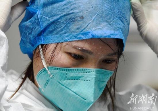 (2月10日,嘉禾县人民医院检验科, 连续工作6个小时的曾梅卸下护目镜、防护帽,豆大的汗珠挂在眉头、脸上。 黄春涛 摄)