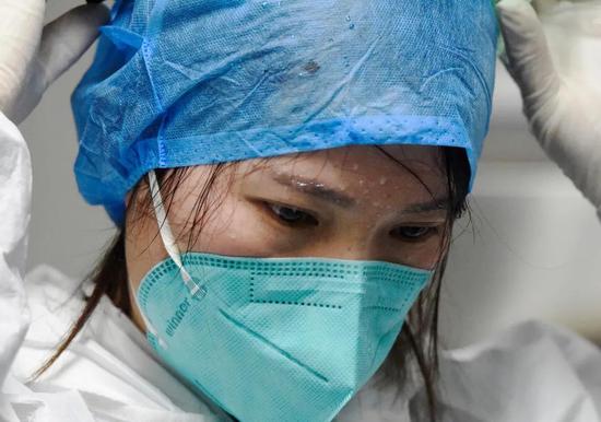  2月10日，嘉禾县人民医院检验科，连续工作6个小时的曾梅卸下护目镜、防护帽，豆大的汗珠挂在眉头、脸上。