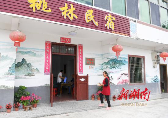 (9月5日,桂东县沤江镇青竹村桃林民宿,老板娘熊桂荣为游客上菜。 湖南日报·华声在线记者 傅聪 摄)