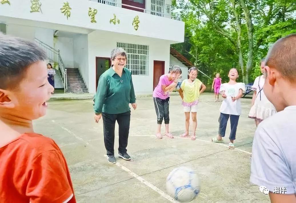 在桐林弘盛希望小学,周秀芳和学生在一起开心地玩游戏。