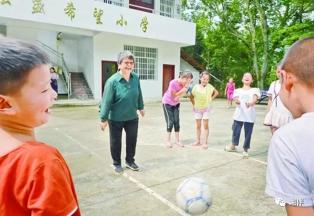 在桐林弘盛希望小学，周秀芳和学生在一起开心地玩游戏。