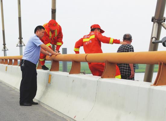  6月30日，岳阳市洞庭湖大桥，消防员在老人欲跳湖的瞬间，迅速翻过护栏拖住老人。图/受访者提供