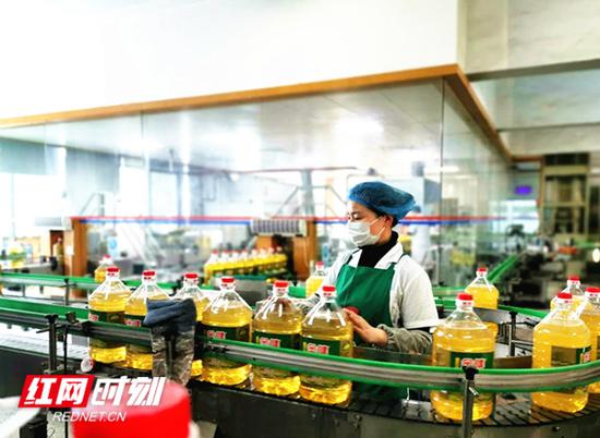 在金健植物油有限公司德山油厂的灌装车间内,戴着口罩的工人们正在生产线上忙碌着。曾玲 摄