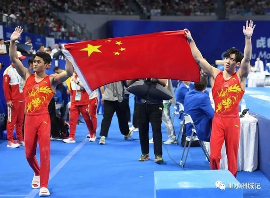 8月4日,张博恒以总分86.733分,夺得冠军。图为张博恒(右)与队友侍聪一同举起国旗庆祝。湖南日报全媒体记者 傅聪 蔡矜宜 摄