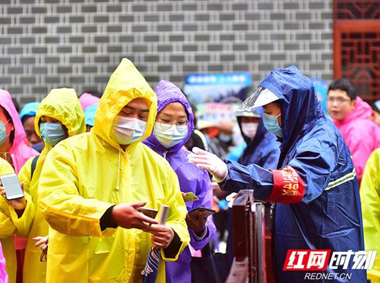 武陵源景区入口外,引导员正在依次引导游客佩戴口罩,出示居民健康码、身份证后再进入游客服务中心。姚冶 摄
