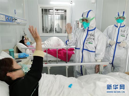 　　2月9日，武汉大学中南医院医护人员在雷神山医院鼓励新冠肺炎患者（手机拍摄）。 新华社发（高翔 摄）