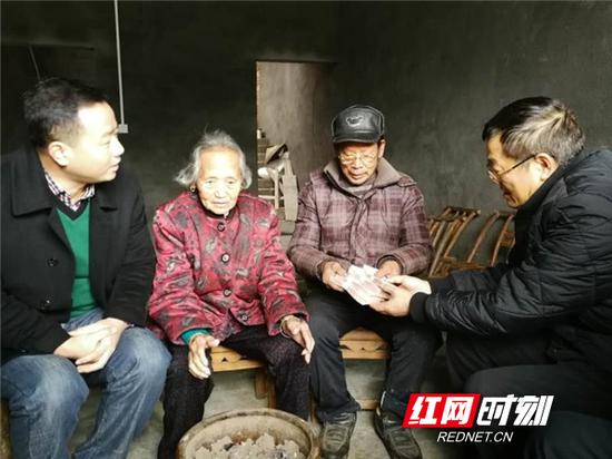 衡阳市委网信办主任王永华（右一）将4万元现金递到唐立生手中，嘱咐他尽快完成房屋的扫尾工程，在春节前搬进新居。