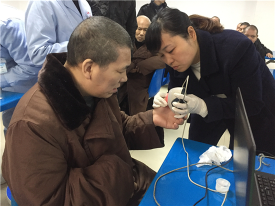 为了拍好身份证照片,民警细心地为流浪乞讨人员整理衣服,摆造型。图片来源:常德文明网