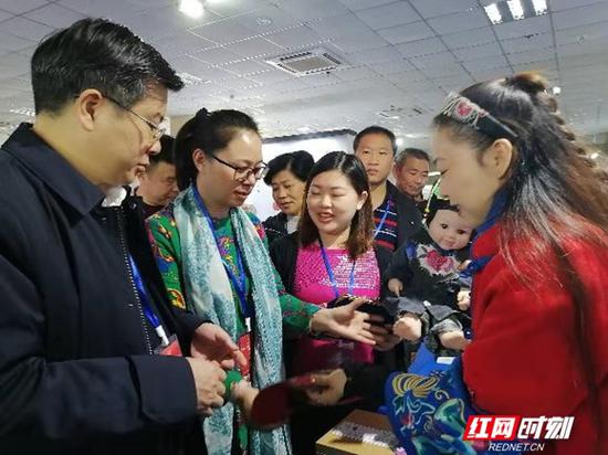 传承人何娟(右一)为参观者讲解大布江拼布绣参展作品文化知识。