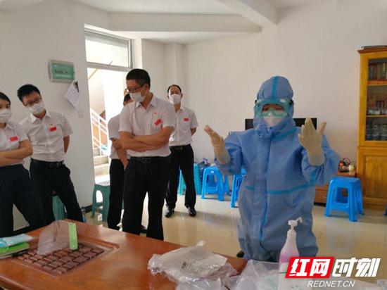 中国(湖南)抗疫医疗专家组徐芙蓉护士长为中国援助赤道几内亚常驻医疗队队员演示穿、脱防护服的流程。