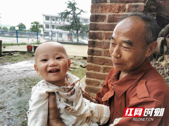 家住岣嵝乡神皇完小附近的董师傅,抱着孙儿小明,满脸都是幸福。