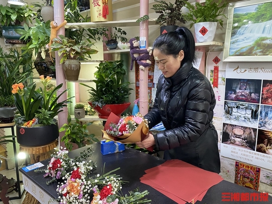 （2月14日，在位于蔡锷北路的一家花店，花店负责人正在为客人整理花束。记者 卜岚 摄）