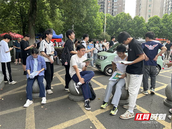 　　衡阳市第一中学考点外，考生们利用开考前的短暂时间翻看笔记、巩固知识点，以从容状态迎接首场考试。（衡阳站记者 王新凤）
