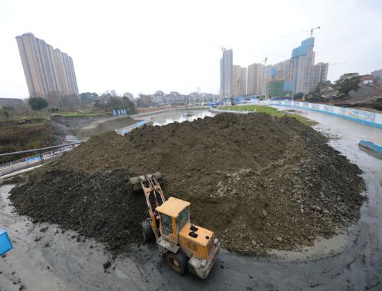 1月7日,在王家河水环境综合治理工程项目部内,推土机将压滤过后的泥饼统一堆放。新华社发(陈振海摄)