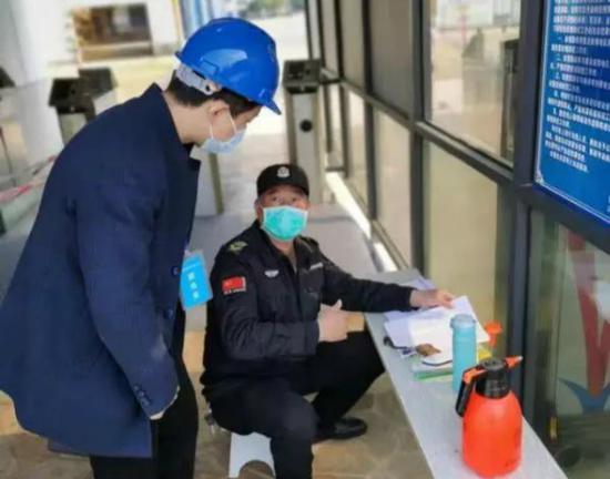 (2月13日,常德市派驻企业防疫联络员彭锋检查常德达门船舶有限公司出入登记情况。来源:常德融媒)