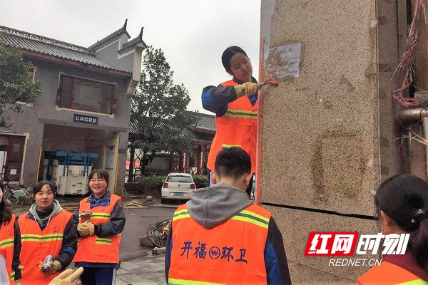 学生们当起了小小环卫工人，用心清理墙上的“牛皮癣”。