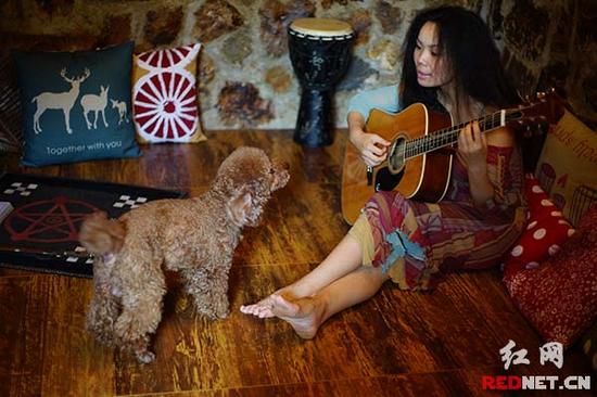lucy弹吉他给爱犬“托比”听。